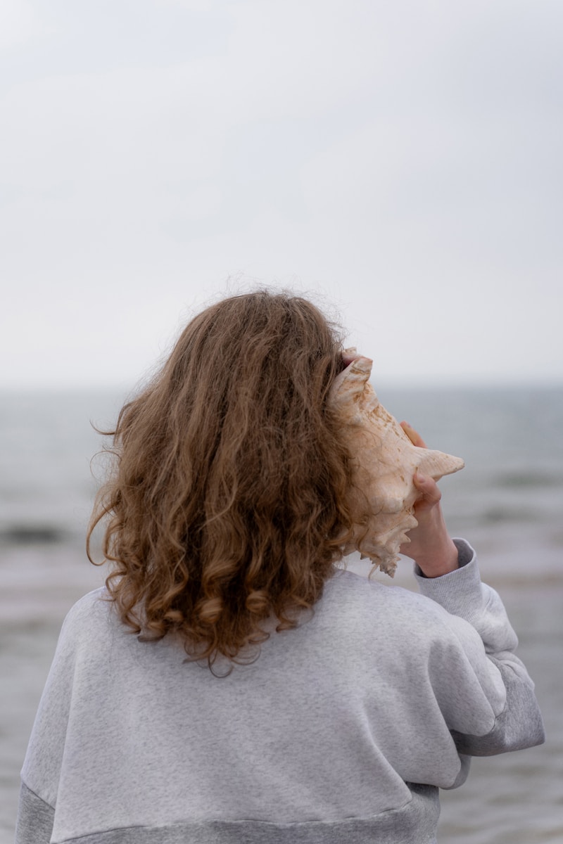 a woman holding a seashell up to her face