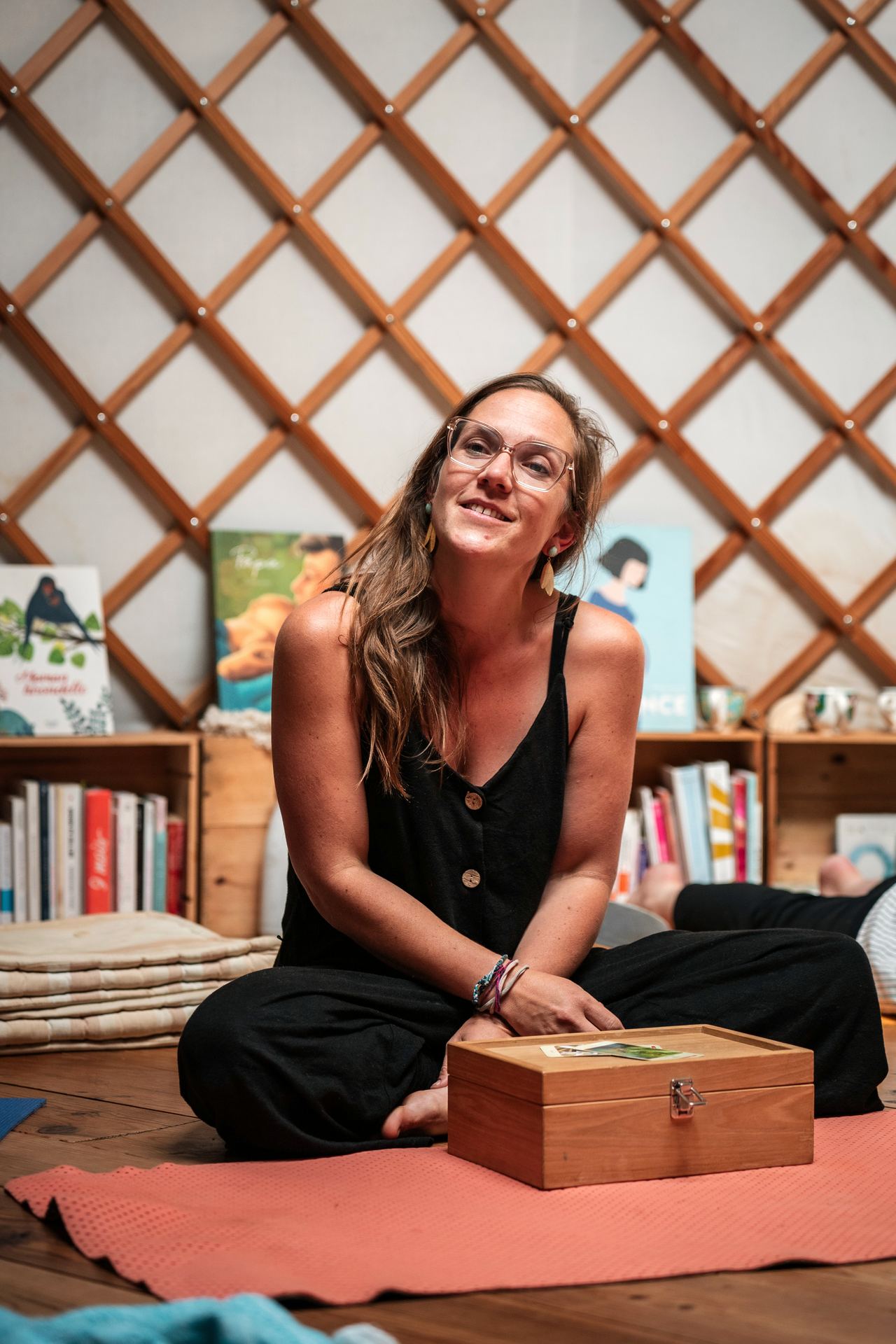 Hannah Stiegler souriante, assise dans la yourte avec le coffret d'élixirs